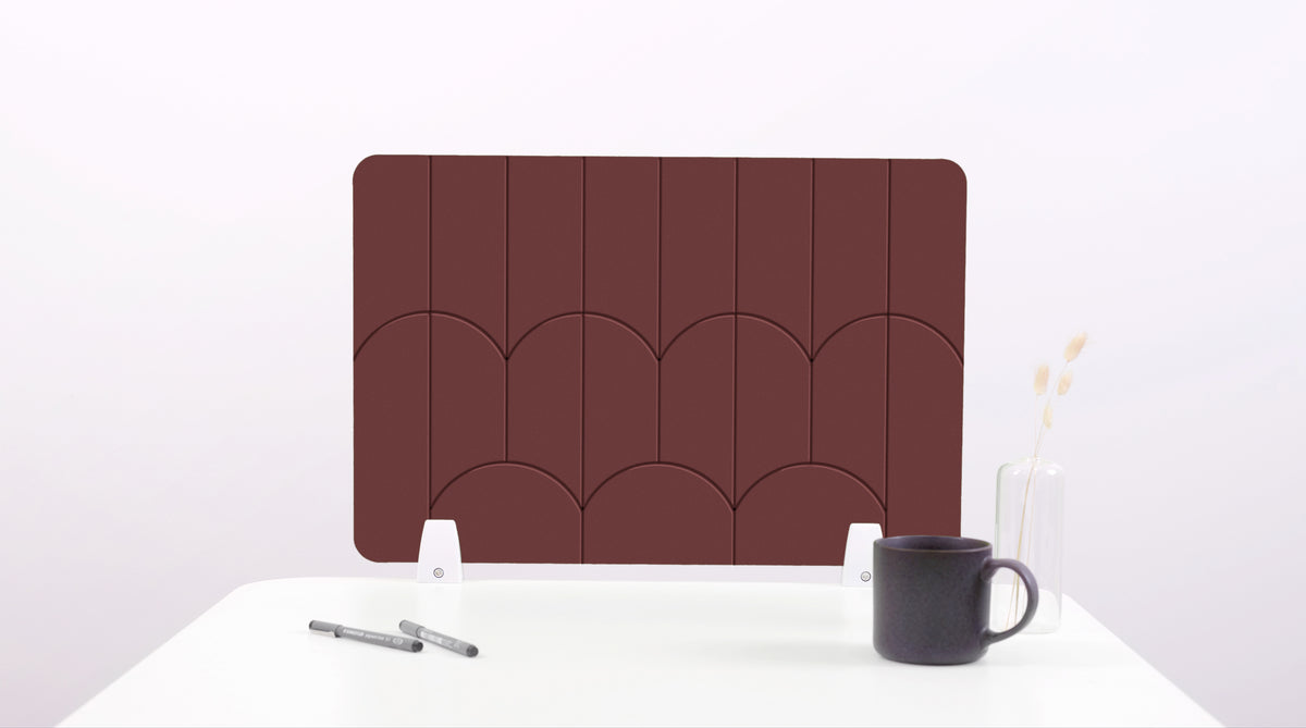 A dark brown colored felt desk divider with a scalloped design of lines and arches. 