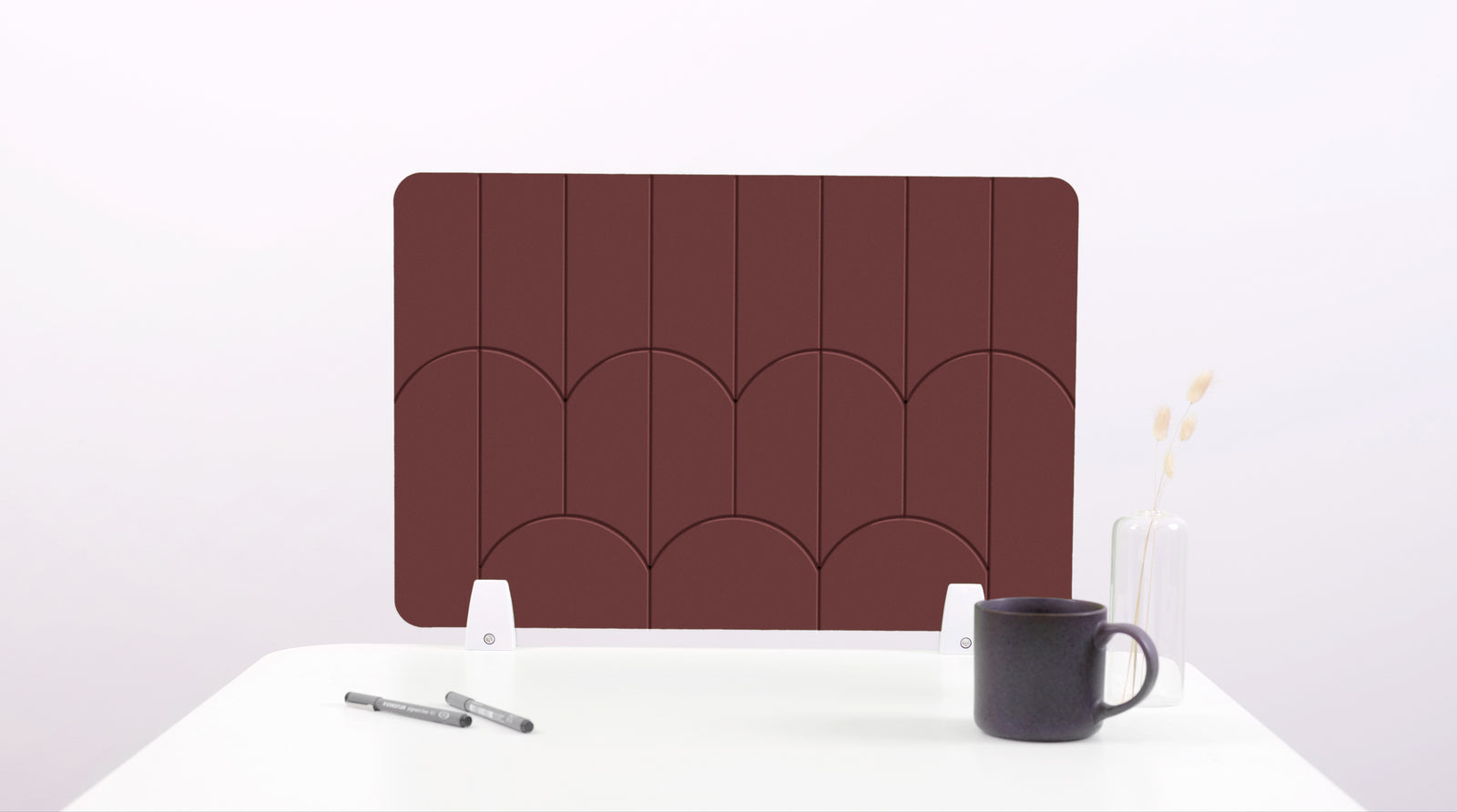 A dark brown colored felt desk divider with a scalloped design of lines and arches. 