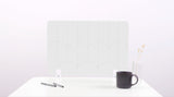 A white colored felt desk divider with a scalloped design of lines and arches. 