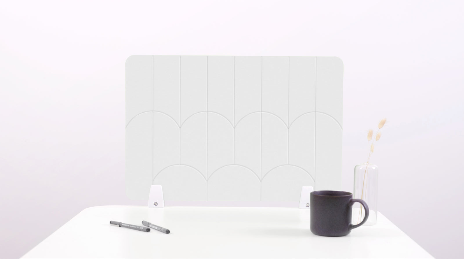 A white colored felt desk divider with a scalloped design of lines and arches. 