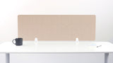A tan felt desk divider with a scalloped wave pattern, mounted on a white desk with a black mug on the left and a small notepad on the right.