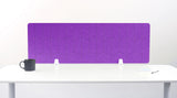 A lavender felt desk divider with a scalloped wave pattern, mounted on a white desk with a black mug on the left and a small notepad on the right.