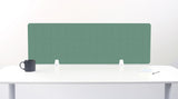 A mint green felt desk divider with a scalloped wave pattern, mounted on a white desk with a black mug on the left and a small notepad on the right.