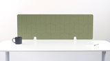 An olive green felt desk divider with a scalloped wave pattern, mounted on a white desk with a black mug on the left and a small notepad on the right.