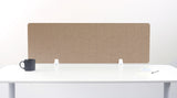 A brown felt desk divider with a scalloped wave pattern, mounted on a white desk with a black mug on the left and a small notepad on the right.