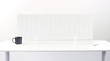 A white felt desk divider with a scalloped wave pattern, mounted on a white desk with a black mug on the left and a small notepad on the right.