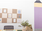 Purple and tan patchwork pinboard mounted on white wall displaying sketches, patterns, and artwork with pushpins.