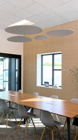 Four gray flat cloud baffles suspended from ceiling above conference table in modern office space.