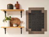 A Felt Right wall art design in shades of brown that is pinnable next to two shelves.