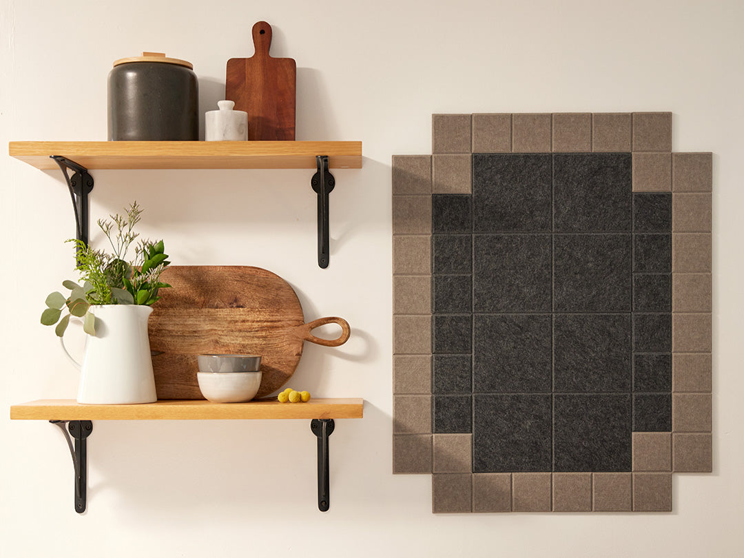 A Felt Right wall art design in shades of brown that is pinnable next to two shelves.