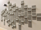 Three-dimensional concrete tiles with angled surfaces creating shadow patterns on a beige wall.