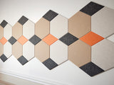 A Felt Right wall art design in shade of cream, orange, and black on light colored wall 