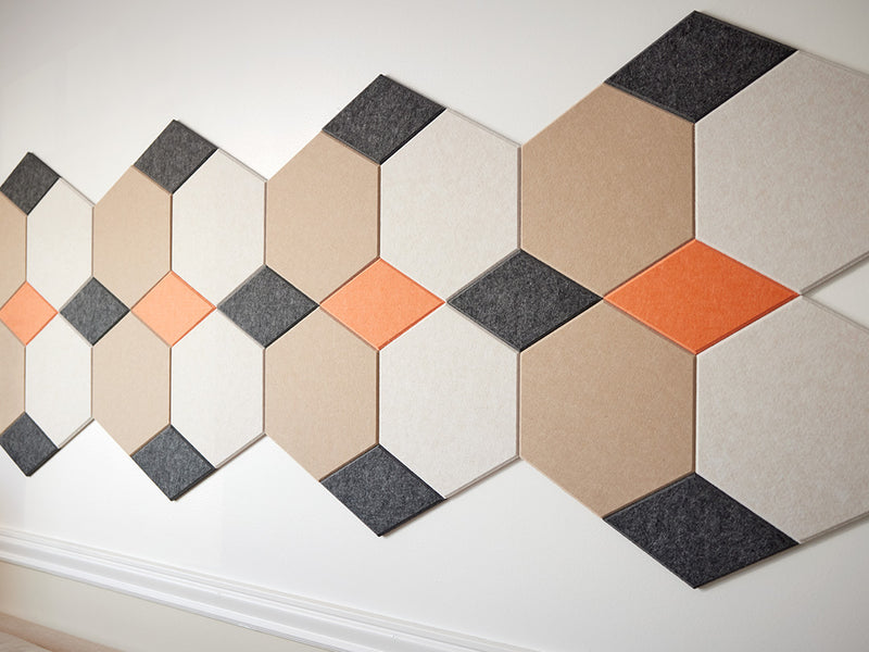 A Felt Right wall art design in shade of cream, orange, and black on light colored wall 