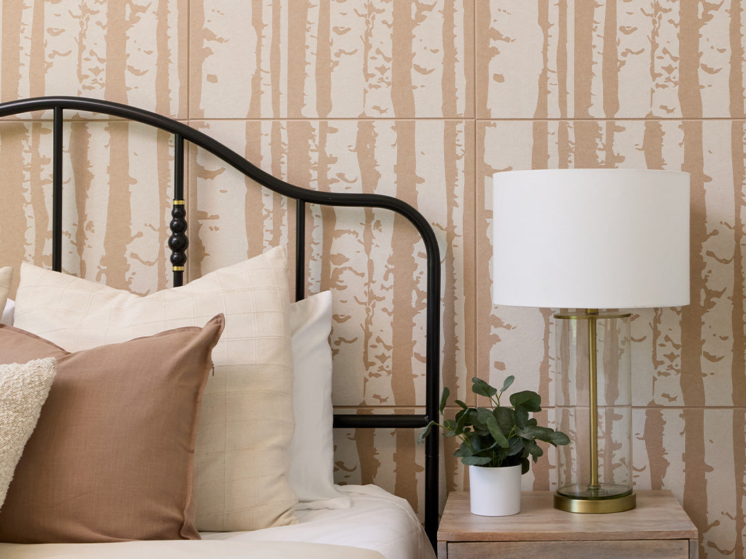 Close up shot of the Felt Right printed aspen tiles on Cashmere colored acoustic panels. There is a bed, night stand, and a lamp in the foreground.