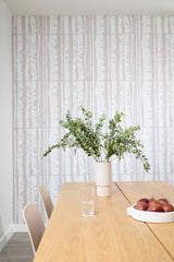 Dining room with a wooden table, vase of flowers, and apples against a patterned wall.