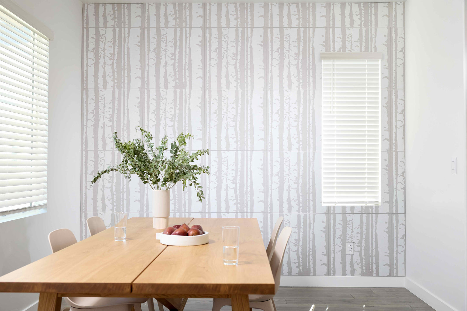 Dining room with wooden table, chairs, and decorative elements against a patterned wall.