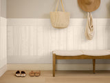 Entryway with a wooden bench, shoes, and bags against a tiled wall.