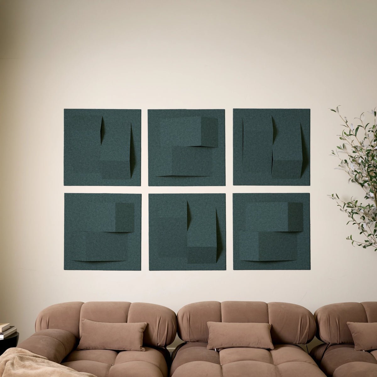 Blue-green acoustic felt tiles with peak dimensions on a wall above a couch