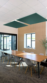 Two dark green square ceiling baffles suspended above a conference table in an office space.