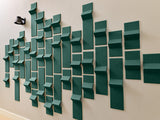 Teal three-dimensional tiles arranged in a staggered wall pattern with varied depths and angles.