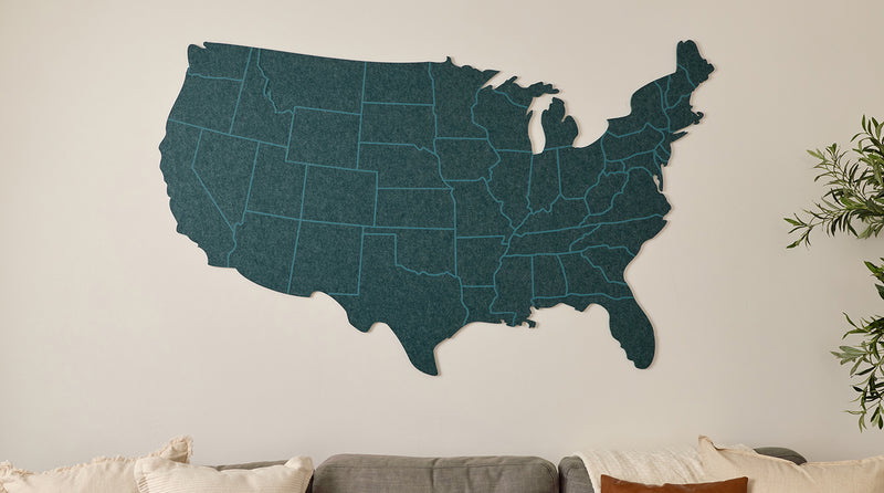 United States map wall decoration on a neutral wall with a couch and plant in the background