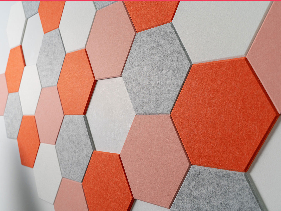 Felt Right wall art design using orange, pink, grey, and white hexagon felt tiles in a honeycomb pattern on a white wall