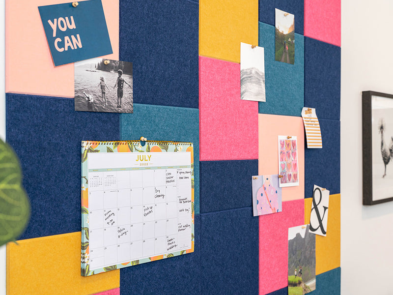 Colorful bulletin board with a calendar and various notes on a wall.