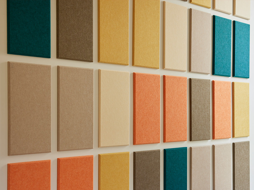 A room with a Felt Right color palette wall art, featuring shades of yellow, orange, red, and green felt tiles