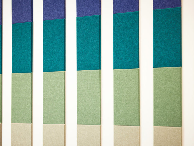 A Felt Right Wall Design in blues, greens, and creams felt tiles in a pattern on a light wall with negative space