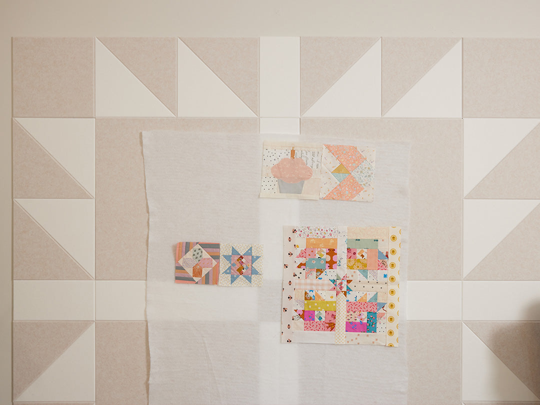 Quilt with geometric patterns on a beige acoustic wall art background