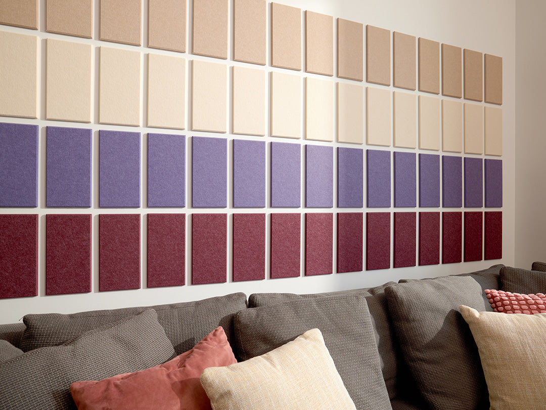 A Felt Right wall art design in shades of cream and purple felt rectangles in an ombre pattern above a couch.