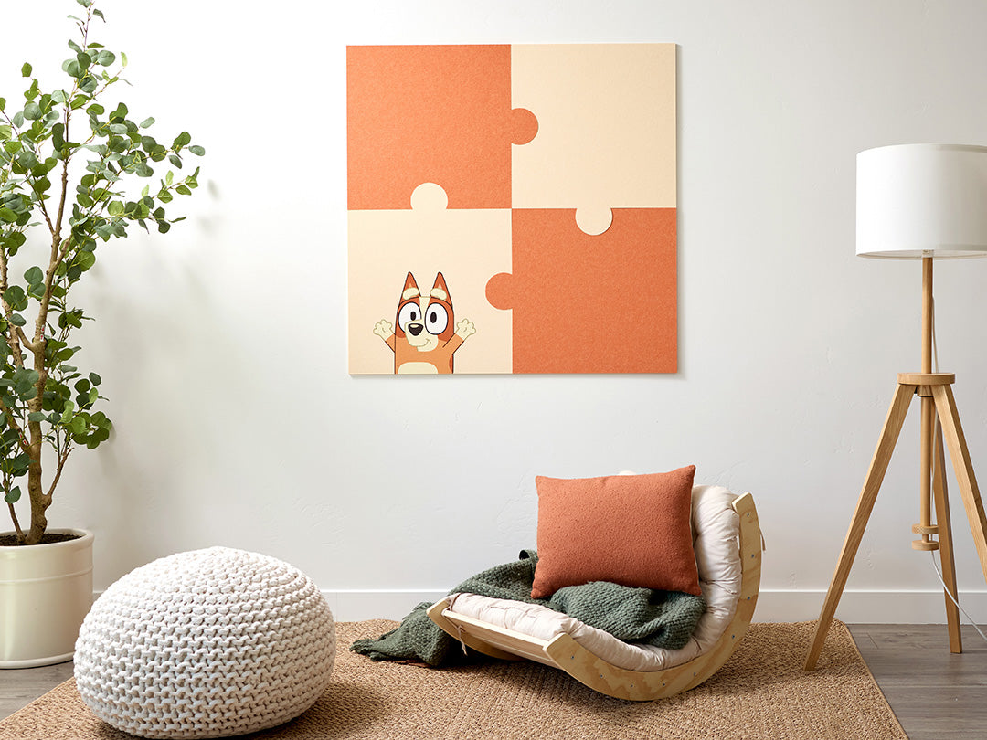 Modern living room with a puzzle-style Bluey wall art piece, chair, and decorative items.