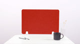 A red felt desk divider placed on a white desk, with a black pen and a cup on its surface.