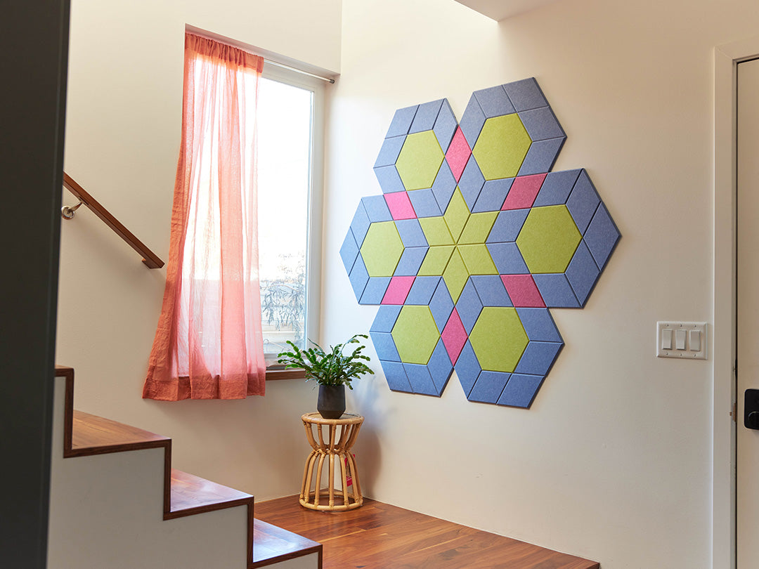 Colorful geometric wall art in a room with a staircase and window.