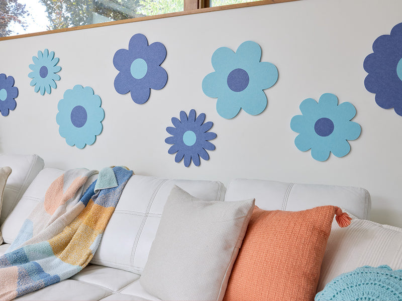 White sofa with colorful cushions and flower decals on a wall