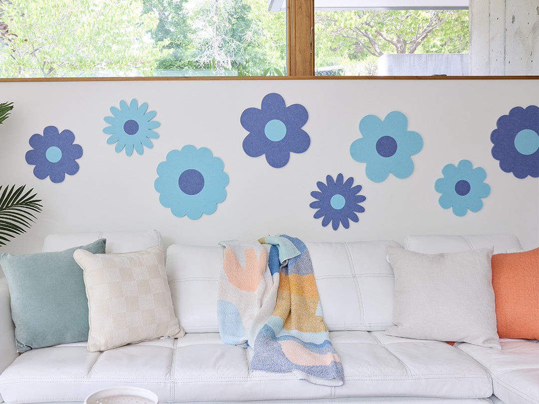 White sofa with colorful cushions and flower decals on a wall