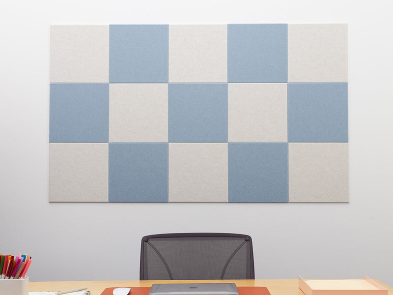 Checkered acoustic panel on a wall above a desk with office supplies.