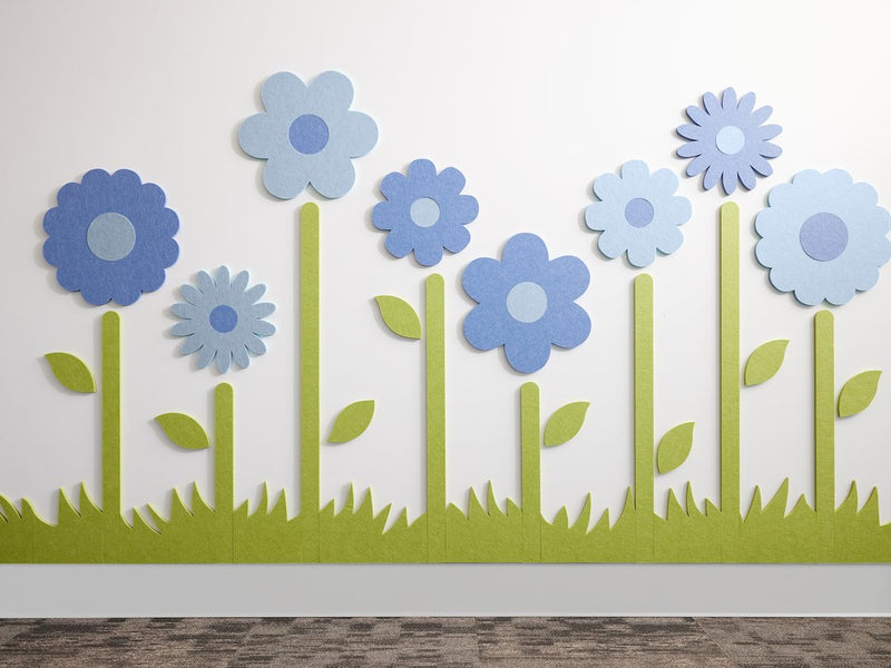 Felt Right wall art design of flowers with stems and grass in shades of blue on a white wall.