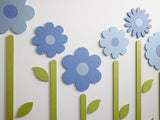Felt Right wall art design of flowers with stems in shades of blue on a white wall.