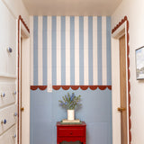 Decorative striped felt wall with a red cabinet and flowers.