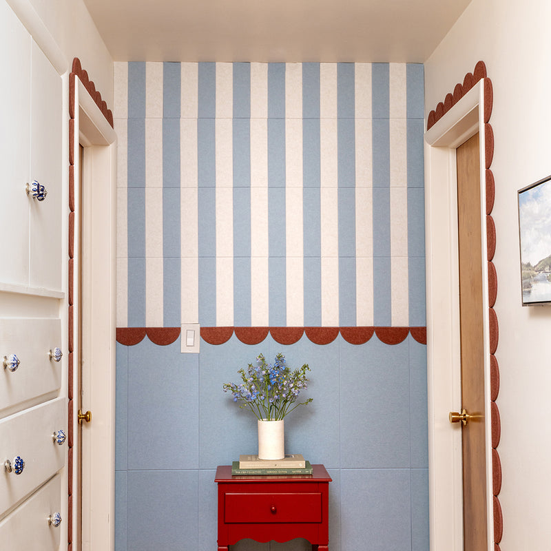Decorative striped felt wall with a red cabinet and flowers.