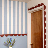 Decorative wall with blue and white striped pattern, wooden door, and small plant.