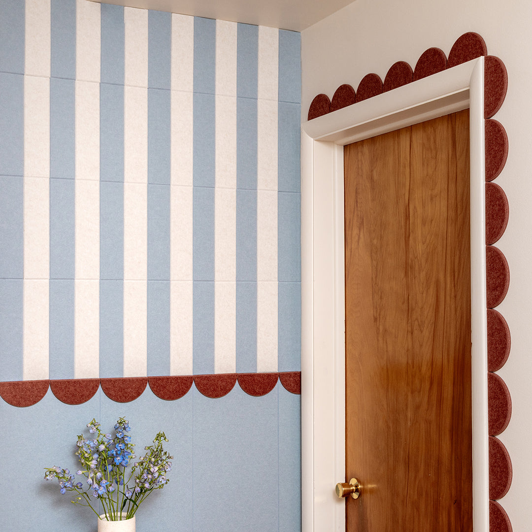 Decorative wall with blue and white striped pattern, wooden door, and small plant.