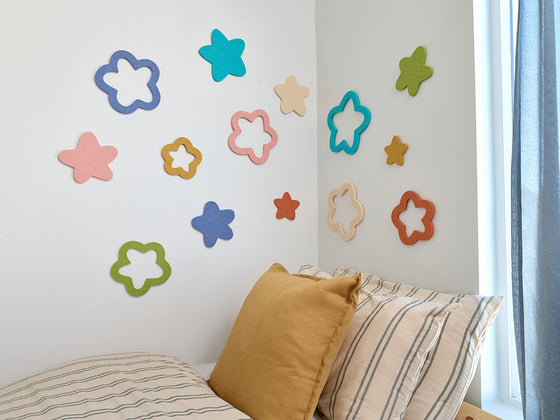 Colorful star-shaped wall decor on a bedroom wall with a bed and pillows.