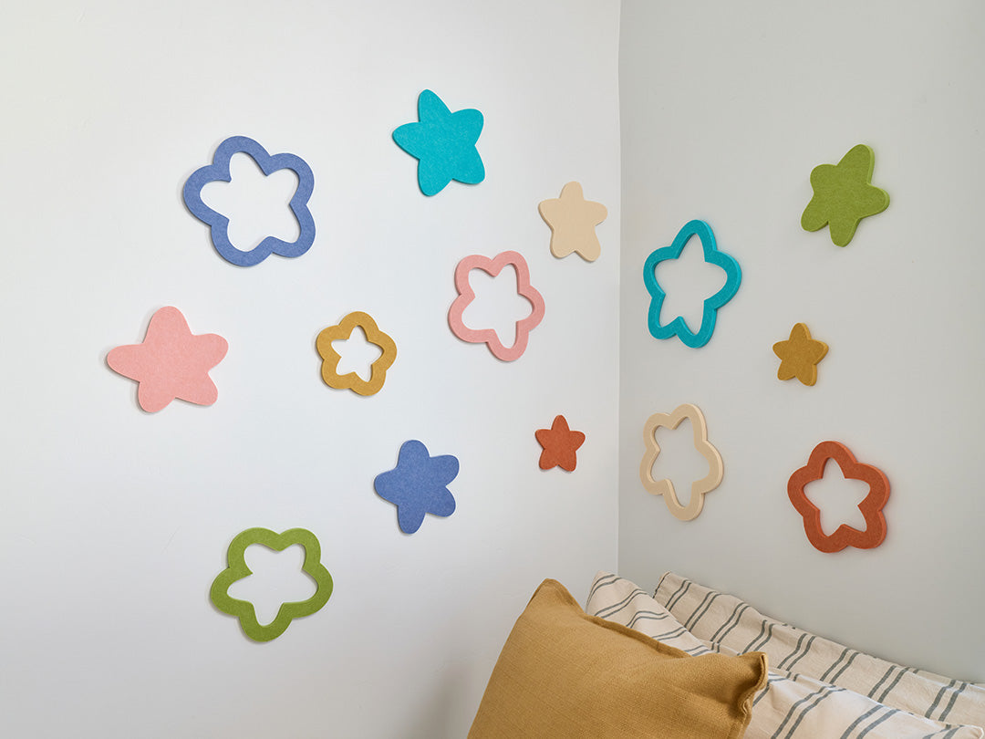 Colorful star-shaped wall decor on a white wall with a pillow and blanket in the foreground.