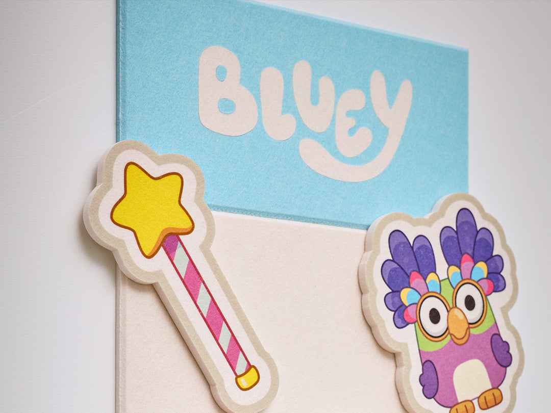 Colorful felt tile on wall with Bluey text and characters.