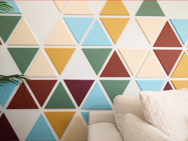 Colorful geometric triangle wall panels in a room with a sofa.