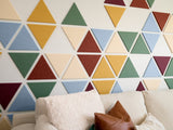 Felt Right wall art design using triangle felt in shades of blue, yellow and red to create a geometric pattern behind a couch.