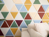 Felt Right wall art design using triangle felt in shades of blue, yellow and red to create a geometric pattern behind a couch.
