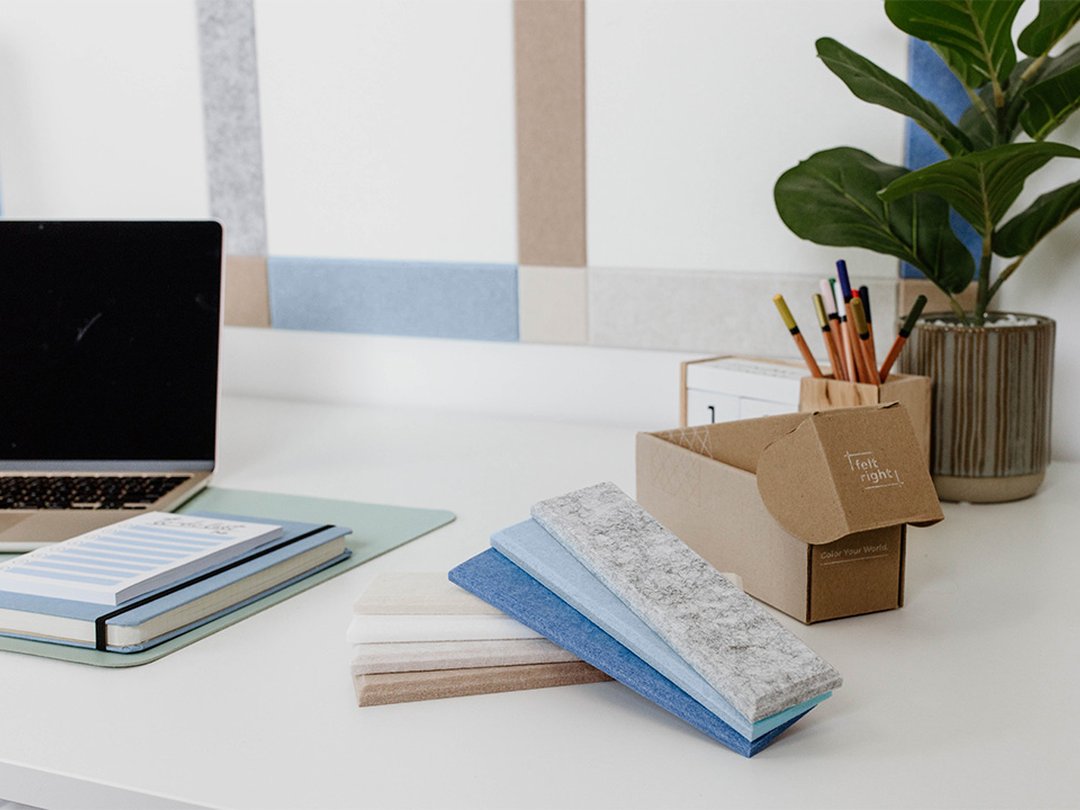 Felt Right wall art design using shades of blue, grey, and cream to created a plaid pattern on a white wall behind a desk with a laptop on it.